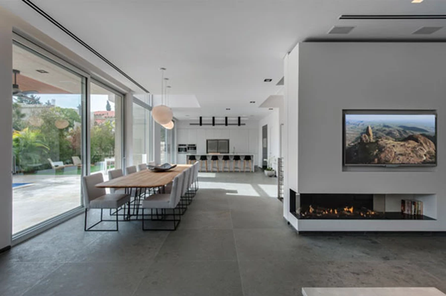 קמין שמשתלב בקיר המפריד בין אזור הסלון וגרם המדרגות נוכח ונחשף מכל פינה במרחב החלל. קמין: 