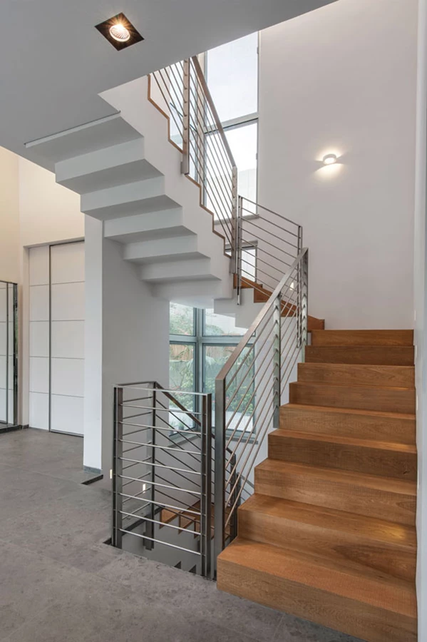 גרם המדרגות: חלל גבוה מלווה בוויטרינה המחדירה אור ואוויר, מדרגות עשויות עץ אלון משמרות מרווח ניתוק בחיבור עם הקיר, ומעקה עשוי נירוסטה בעיצוב נקי קווים. מעקה נירוסטה: 