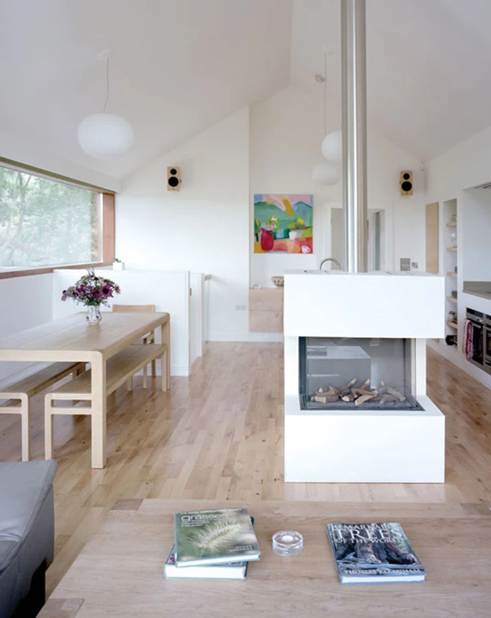 האח המופעלת בגז משמשת כנקודת מיקוד בחלל המגורים ומשתלבת באופן מושלם באי של המטבח.