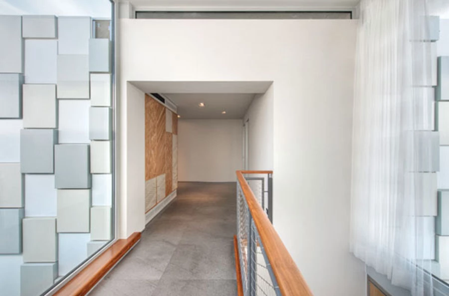 זרימת הקומה העליונה שתחילתה היא גשר תחום בשקיפות שצדו האחד צופה לנוף הים והשני לגינה. משמאל נראות קוביות הפח המשובצות במעטפת כעוד ממד מעשיר: מופיעות בשלושה גווני אפור,