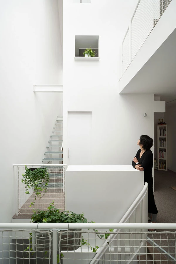 מופע החלל: בהיר, פתוח ומאופיין בממד אנכי. עציצים ירוקים על סורגי מעקה המדרגות יוצקים תוכן של חיות טבעית למארג הלבן.