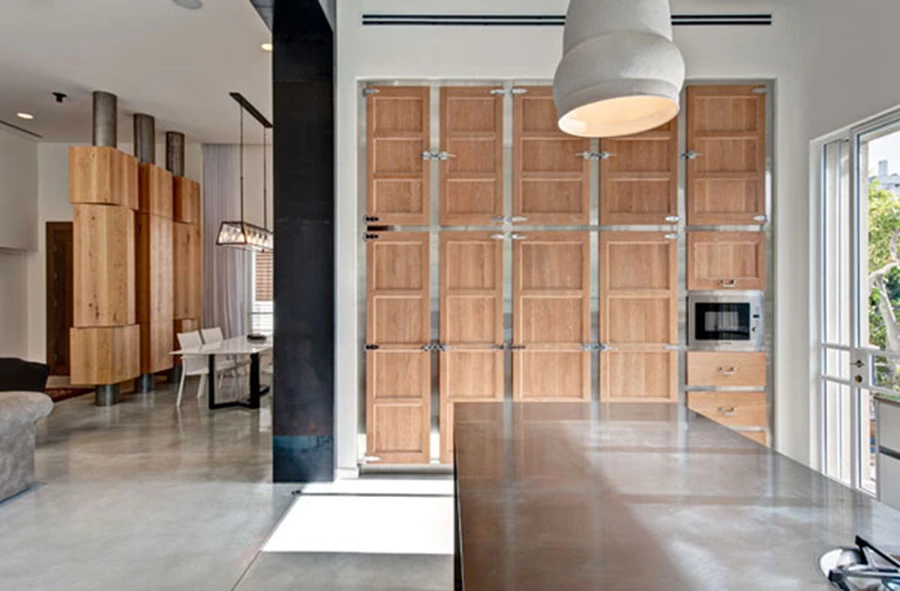 המטבח: אזור פעיל בחיי הבית.  יחידת אי גדולה מאד עשויה נירוסטה עם כיריים משוקעים בתוכה מודגשת באמצעות שלושה גופי תאורה גדולים מעליה. יחידת הקיר הגדולה משלבת חזיתות עץ וידיות נירוסטה ומהדהדת מראה תעשייתי. מטבח: