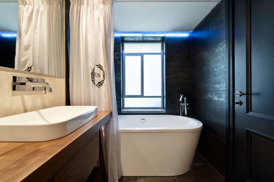 חדר הרחצה הצמוד לחדר: חיפוי קיר שחור, אמבט וברז בסגנון פרי סטנדינג. אביזרים סניטאריים: נגב.