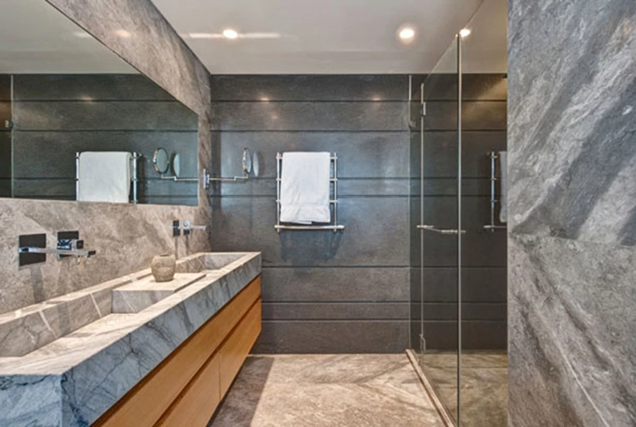 חדר הרחצה ביחידת ההורים: חיפוי שיש בשני גוונים, יחידת כיור ארוכה בסגנון שוקת ונגרות שתוכננה בהתאם. משטחים: 