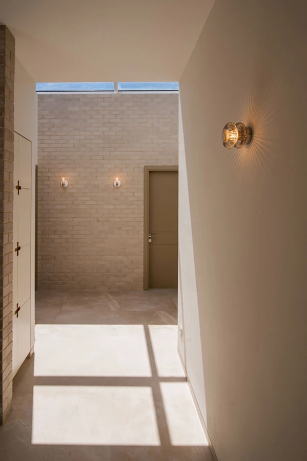 המבואה המשותפת באזור הילדים, שבהיקפה סדורים החדרים: חיפוי לבנים וסקיילייט המחדיר אור יום ומייצר תחושת חוץ לא מצופה.