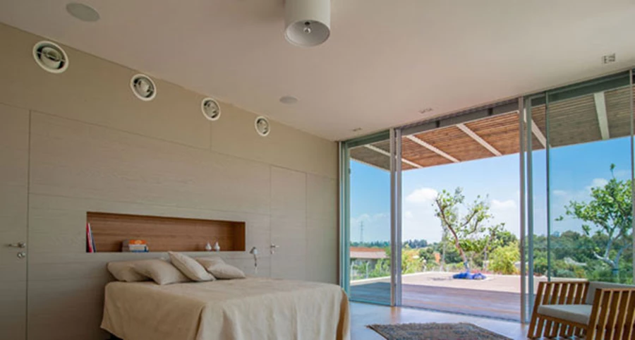 אזור השינה: קיר נגרות המהווה גב למיטה, ובו משתלבות דלתות כניסה לאזור ארונות-הלבשה הממוקם מאחוריו וגומחה קטנה מחופת עץ מעל המיטה.