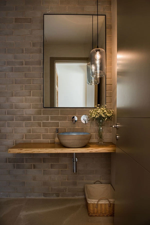 שירותי האורחים: אסתטיקה מוקפדת משלבת חיפוי לבנים ומדף עץ מינימליסטי עם כיור בהנחה עליונה וגוף תאורה תואם: 