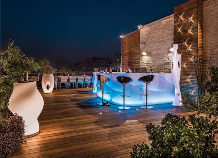 לב המרחב: הבר שעוצב ייעודית מחומר פלסטי מותאם לסביבת חוץ. תאורת לד המותקנת בתוכו הופכת אותו לסוג של גוף תאורה, וכך גם הכדים הגדולים ופסל דמות האישה. גופי תאורה על חיפוי סרגלי העץ בקיר מנצנצים כעין כוכבים. בר, כדים ודמות אישה: