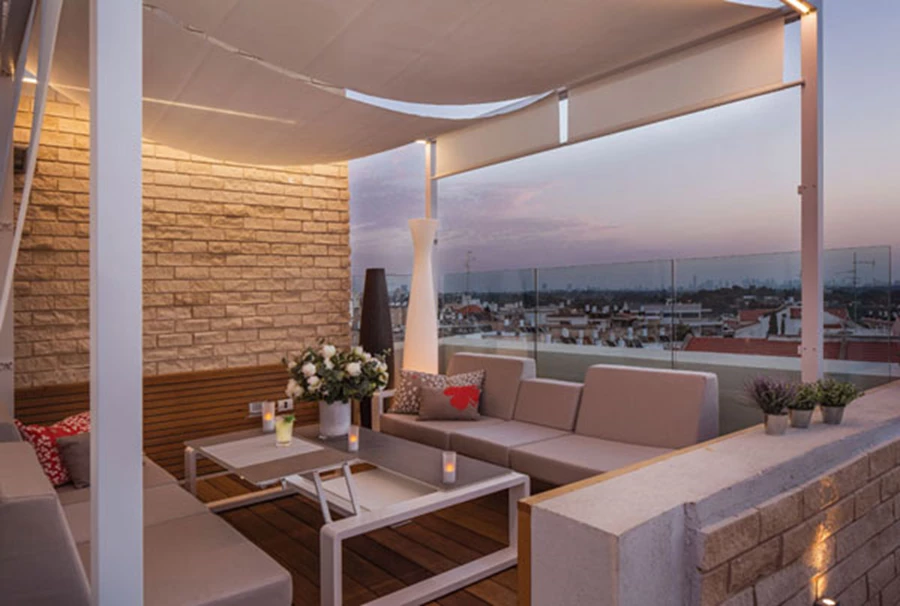 פינת הסלון: מרחב ביתי לכל דבר. תחומה בגזיבו המשווה לה אינטימיות, סרגלי עץ משמשים כחיפוי מצניע כבלים, קיר בריקים המוסיף עניין ויזואלי, ופריטי ריהוט מסוגננים.