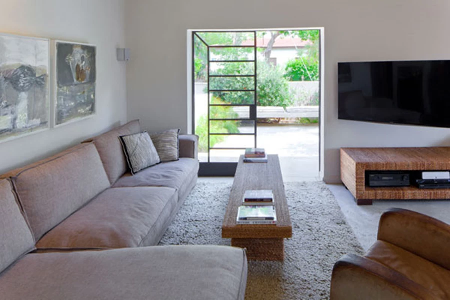 פינת הישיבה בסלון: עיצוב נינוח וחיבור ישיר עם החוץ. ריצוף בטון יצוק, תאורה היקפית המעצימה תחושת מרחב ופרופיל בלגי בפתחים, שנותרו כשהיו ורק חודשו באמצעות צביעה.