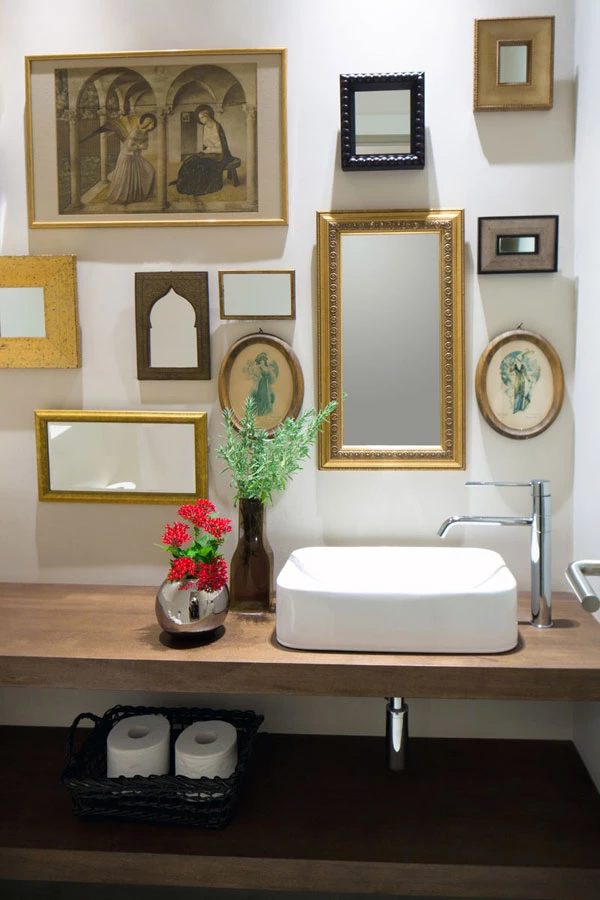 שירותי אורחים: מדפי עץ מקיר לקיר, ומקבץ חינני של מראות ותמונות על הקיר.