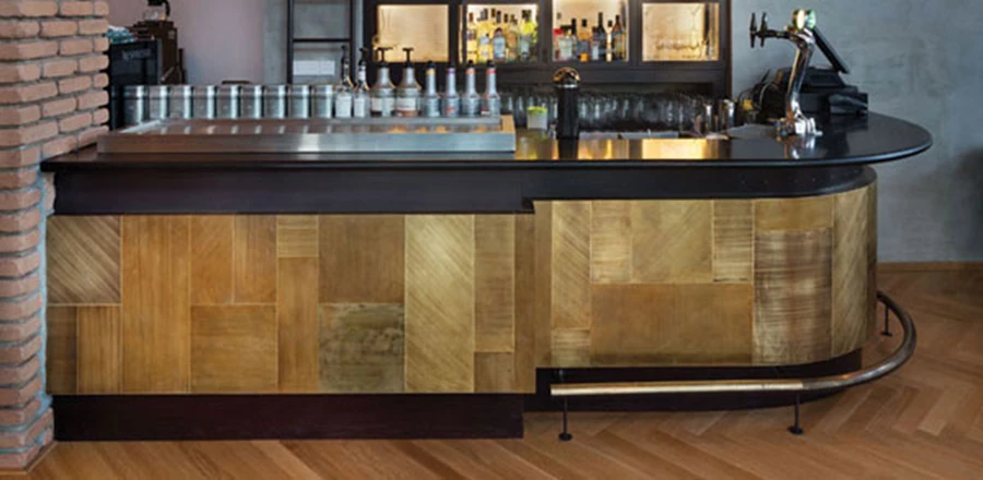 חזית דלפק הבר: לוחות פליז שנטבלו בחומצה לפרקי זמן שונים ולאחר מכן שויפו בנייר לטש בעוצמות משתנות וכיוונים שונים. התהליך שיצר הבדלים בין לוח ללוח, העמיק את גונם והעצים את ערכי הברק שלהם, הניב החזרי אור שונים.