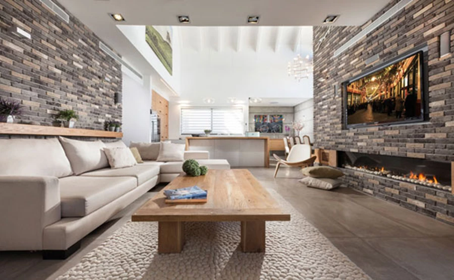 אזור הסלון: קירות מחופים בלבני פירוק אפורות שבאחד מהם משתלבים קמין ומסך הטלוויזיה. צבעוניות מאופקת-רגועה ונגרות מעץ אלון צרפתי. חיפוי לבנים: