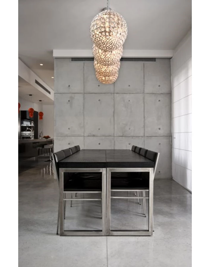 פינת אוכל בבית בהוד השרון - משחק בין גוף תאורה דקורטיבי לבין ההבטון החשוף שמקבל את האור הטבעי מבחוץ צילום- מושי גיטליס