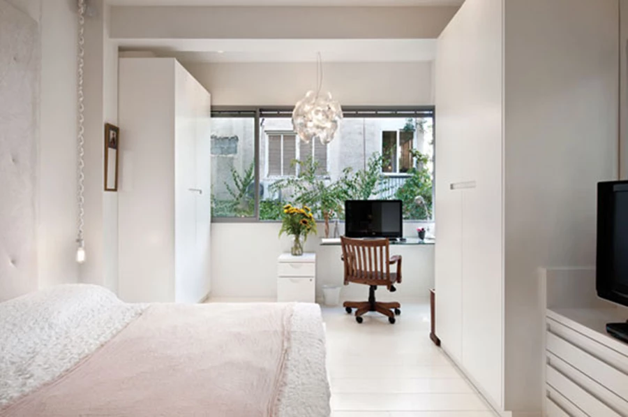 חדר השינה בו משתלבת גם פינת העבודה הממוקמת בעומק השטח מתחת לפתח חלון רחב.