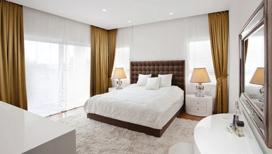 יחידת השינה: עיצוב אלגנטי משלב טקסטילים קלאסיים בגוונים כהים במיטה המרופדת ובוילונות.  מנורות צד ומראה במראה מתכתי עשיר משלימים את המראה.