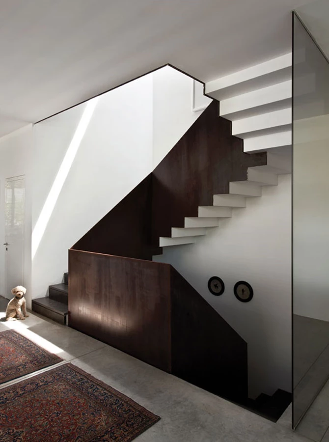 גרם המדרגות המוביל לקומה העליונה: מעקה עשוי פלדת קורטן יוצק עניין שונה לאווריריות השקופה. האור החודר מכיוון הבריכה ומסקיילייט עליון מייצר ברק ודיגומי אור על משטחי החומר והקיר.