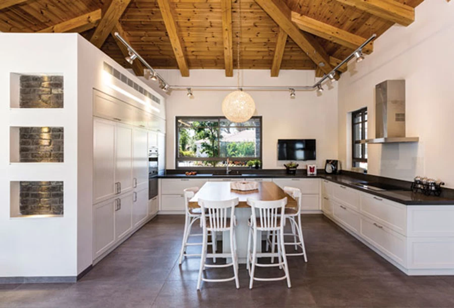 המטבח: זיקה לסגנון כפרי. חזיתות בגימור אפוקסי לבן, משטח עבודה שחור (בזלטינה), יחידת אי משטח בוצ