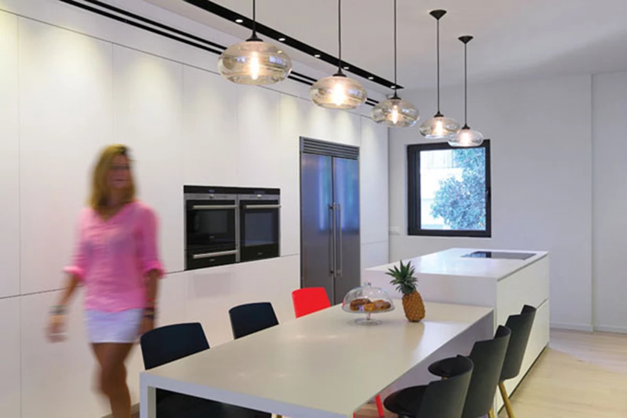 צדו השני של המטבח: יחידת קיר לבנה בתוכה משתלבים מכשירי החשמל, כשמיקום היחידות כולן מייצר בחללו שתי שדרות נוחות לתנועה. כיסא יחיד בורוד עז משתלב עם כיסאות שחורים כקריצת הפתעה. יחידות האי והקיר: