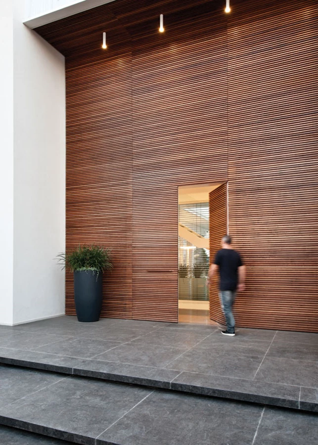 דלת הכניסה נטמעת בתוך חיפוי העץ כחלק אינטגראלי.