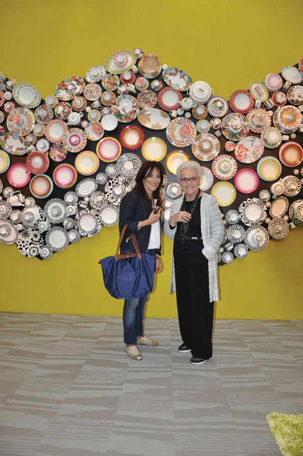 רוזיטה מיסוני על רקע קיר הצלחות שנוצר כשת