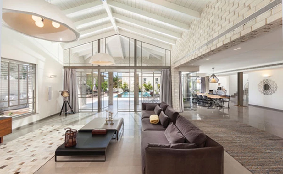 שקיפות ופתיחות מחליפות את מופעה האטום של החזית. משמל נראה הסלון הממוקם בגוש הקטן, ומימין פינת האוכל ומעבר לשאר אזורי הקומה הממוקמים בגוש הגדול. ריצוף באריחי שיש אפורים ופרופיל בלגי בויטרינות. פרופיל בלגי: