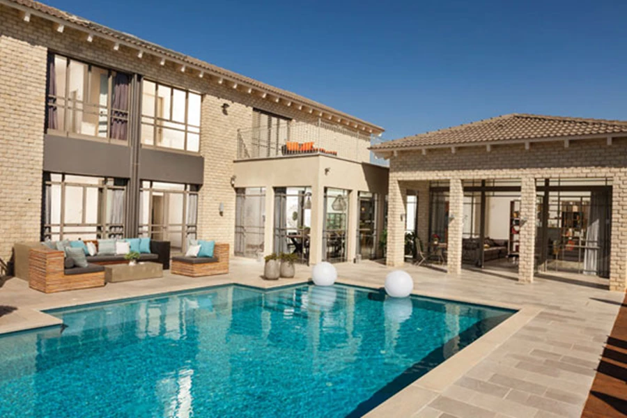 החזית האחורית: שינוי דרמטי מהקדמית והעצמה של המראה הכפרי. שטח רחב ידיים המשלב אזורים מרוצפים באריחים או דק, אזורים מגוננים, פינות ישיבה, אוכל ושיזוף, אזור בישול נוח ומקלחון לשרות המשכשכים בבריכה הגדולה.