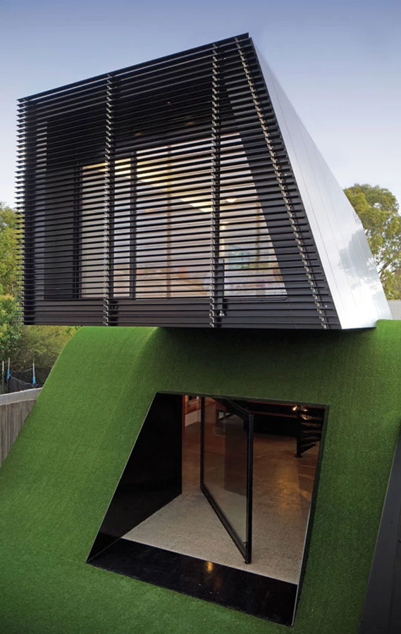 מבט משטח החצר אל חלקה האחורי של תוספת המבנה, כאשר רפפות  התריס של חדר השינה פתוחות.