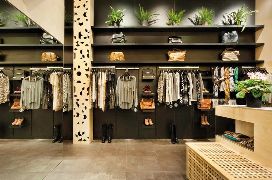 על רקע הקיר השחור: מדפי תצוגה שחורים ונגיעות ירוקות שמשתלבות עם פריטי האופנה.