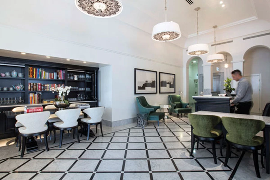 מבואת הכניסה ואזור הקבלה: תקרות גבוהות וריצוף שיש קררה נאמן למקור המבני.