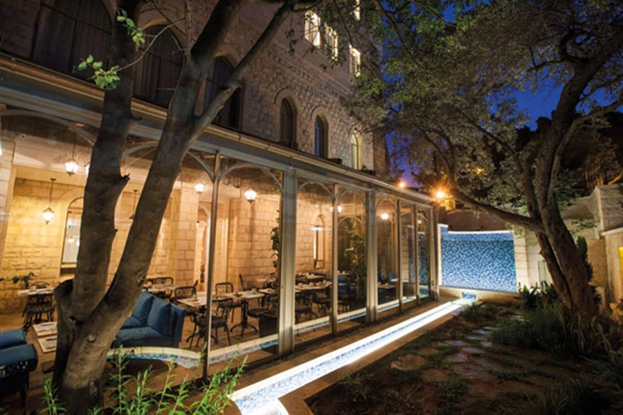 מרחב הגינה ביציאה מחדר האוכל: עצים עתיקים ואמת מים מייצרים פינת חמד פסטוראלית. הקירוי הקל מוסט בעונת הקיץ ומאפשר ליהנות מישיבה בחוץ.