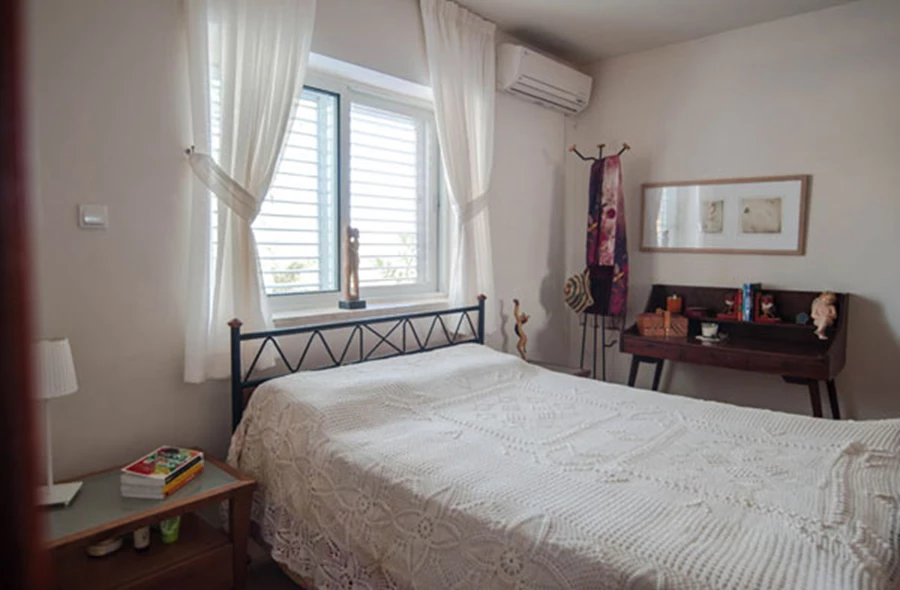 חדר השינה נצבע בצבע בהיר וילונות בהירים וגוף תאורה צבעוני מוספים אור