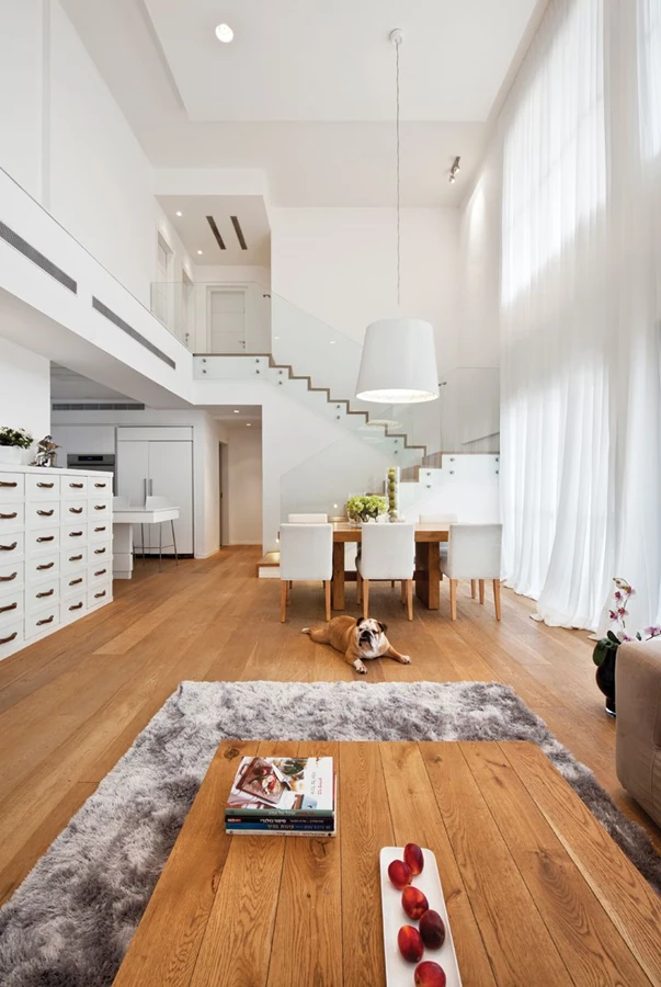 מבט “חוצה חלל” מפינת הסלון אל גרם המדרגות הצמוד לקיר. מעקות זכוכית: “שבירו”, פרקט: “פרקט בשרון”