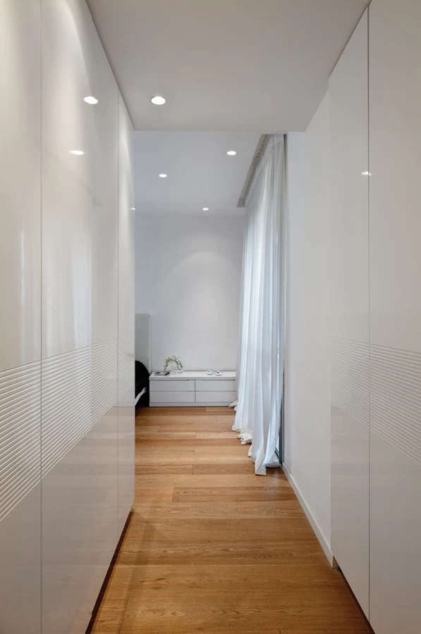 החלל “נעטף” בארונות קיר תוך יצירת מעין מבואה, כשדלת הכניסה אליו מוטמעת כאחת החזיתות.