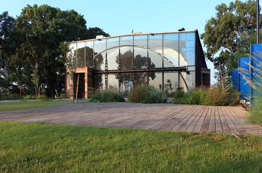 בתוך החזית השקופה משתלבת דלת ענק מקושתת עם פתיחת פיווט המייצרת מפתח של 21 מטר וקושרת את הפנים והחוץ לרצף אחד.