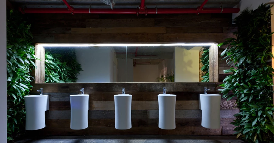 אזור שירותי הגברים: תשתיות, מערכות ואביזרים סניטאריים המיישרים קו עם תפיסות מקיימות, קיר ירוק וקריצה עיצובית. ברזים ואביזרים סניטאריים: “זהבי עצמון”.