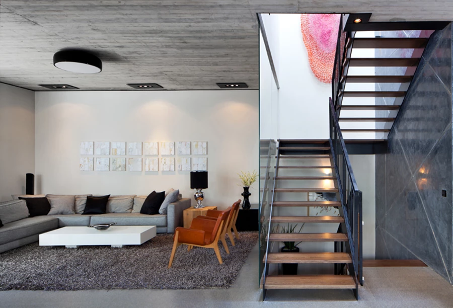 פינת הישיבה בסלון: קונטרס מעניין בין קירות הגבס הלבנים והחלקים לבין תקרת הבטון, גופי תאורה שתוכננו ייעודית כמסגרת פלדה דקה המרחפת במנותק מהתקרה, ופריטי ריהוט מסוגננים. פריטי ריהוט: