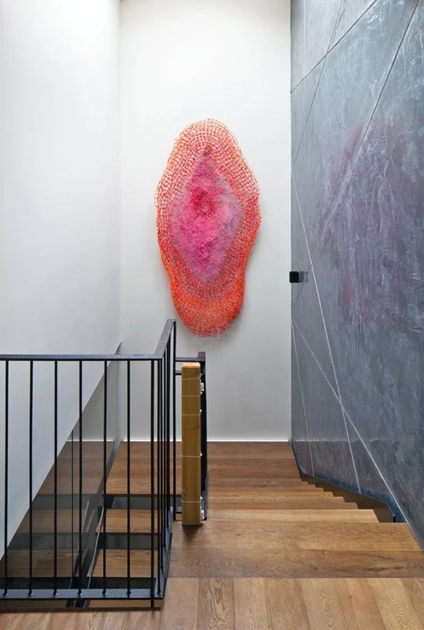 גרם המדרגות: קונסטרוקציית פלדה ומדרכים כקוביות פרקט דקיקות ומרחפות. קיר כהה מלווה את חלל המדרגות מהמרתף ועד הקומה העליונה.