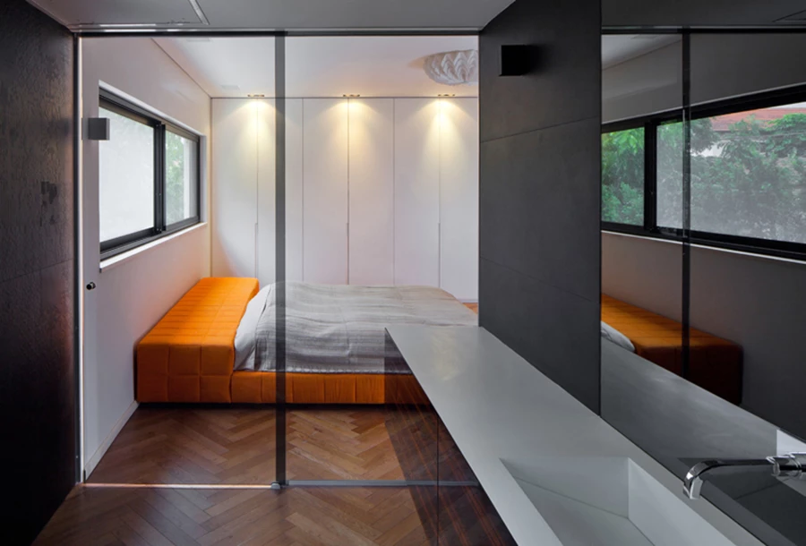 יחידת ההורים בקומה העליונה: מחיצת זכוכית מפרידה בין חלל החדר ואזור הרחצה המעוצב בסגנון אלגנטי- דרמטי בפלטת צבעים כהה. אביזרים סניטאריים: