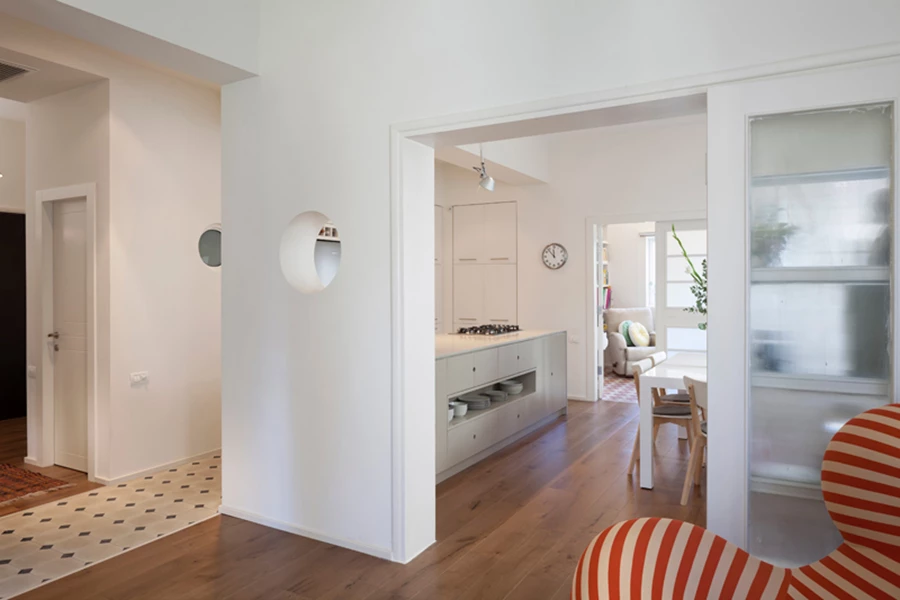 מבט מחלל הסלון אל עבר חדר האוכל והמטבח: מיקומם הועתק אל חלל מסדרון שבוטל והפך לשדרה משמעותית בהתנהלות המרחב.