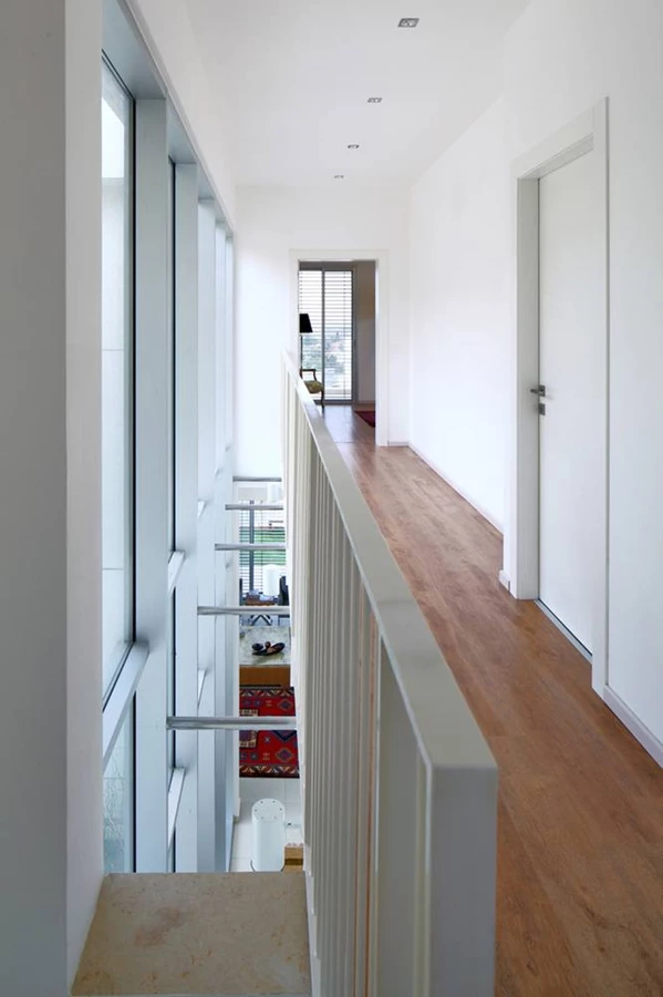 קומה העליונה: ריצוף פרקט וציר תחום בשקיפות החזית הקדמית שלאורכו ממוקמים החדרים. מרווח פתוח שנשמר בינו לבין החזית השקופה ומאפשר קיום קשר עין עם קומת הכניסה מעצים תחושת זרימה ופתיחות.