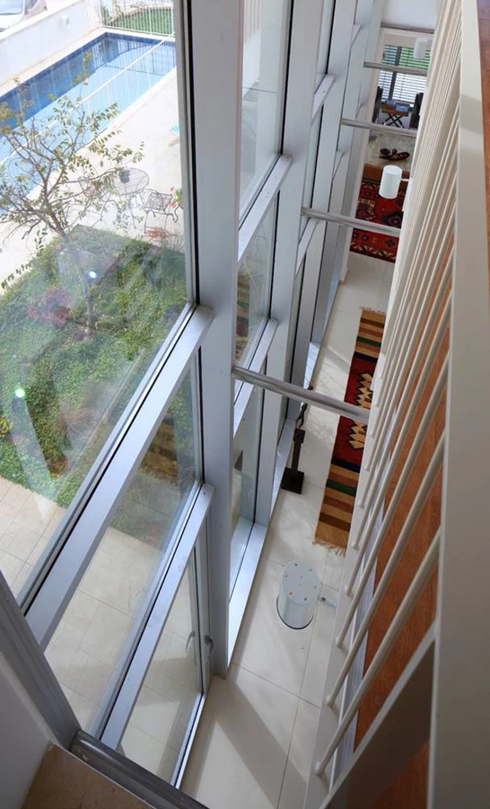 קומה העליונה: ריצוף פרקט וציר תחום בשקיפות החזית הקדמית שלאורכו ממוקמים החדרים. מרווח פתוח שנשמר בינו לבין החזית השקופה ומאפשר קיום קשר עין עם קומת הכניסה מעצים תחושת זרימה ופתיחות.