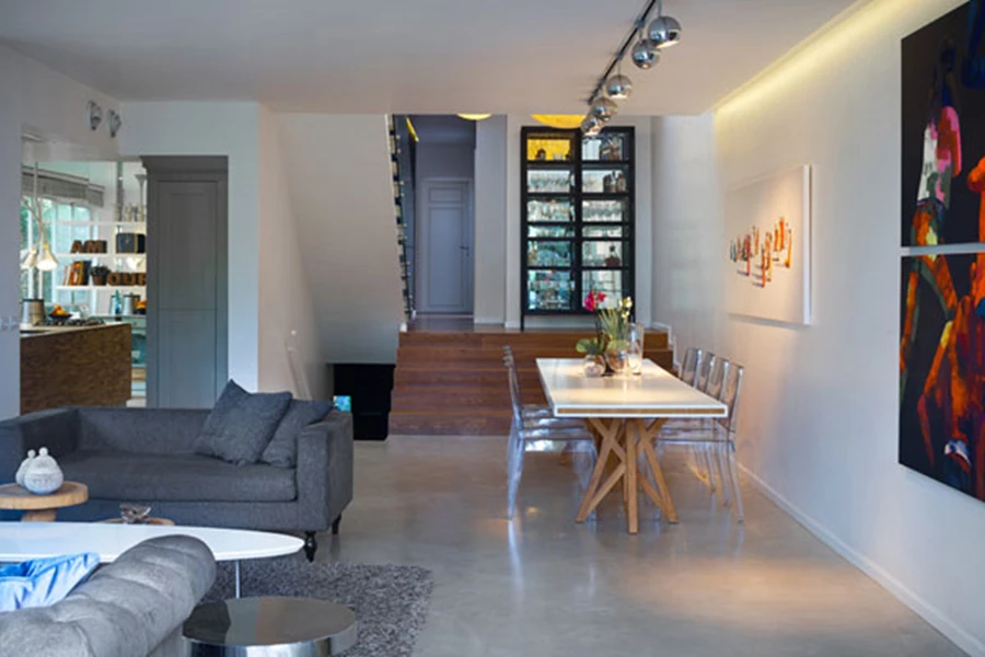 מבט מעומק הסלון לפינת האוכל, המטבח שמשמאלו גרם המדרגות המוביל מטה לקומת המרתף והעלייה למלפסי החדרים.