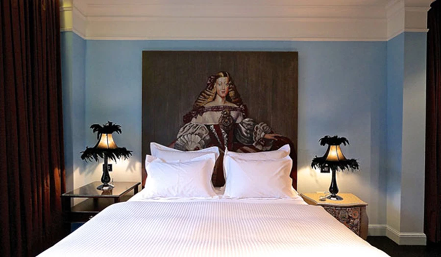 חדר שינה במלון עלמה: ראש המיטה עם ציור על עץ. צילום: איתי סיקולסקי.