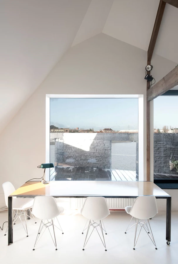 מבט מפינת האוכל אל המרפסת בקומת הגג. סביב השולחן: כיסאות אייקונים בעיצובם של צ