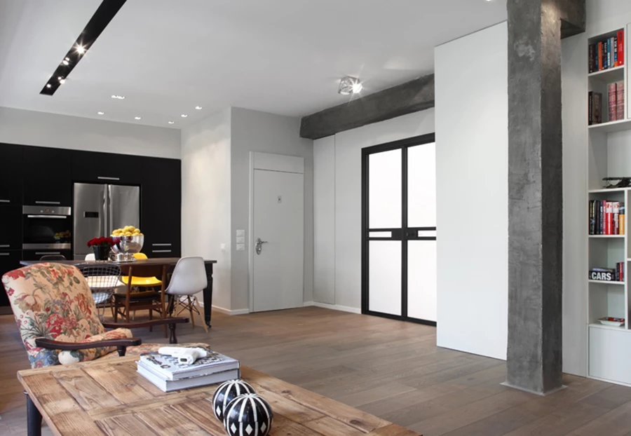 מבט מדלת הכניסה אל חלל המגורים: מימין ממוקמים המטבח ופינת האוכל ובעומק הסלון. משמאל נראות דלתות חדר העבודה, אשר פתיחתן