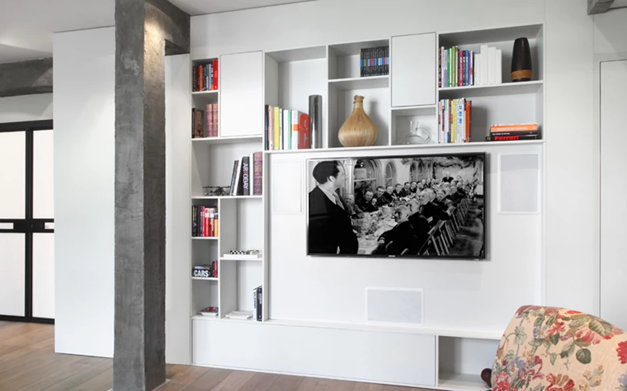 יחידת נגרות מובילה מדלת הכניסה אל חדר השינה שבעומק החלל כעין חוט מקשר. באזור הסלון מנוצלת היחידה לאחסון מערך הבידור ולתליית מסך הטלוויזיה, וכוללת גם חללים פתוחים להצבת ספרים וחפצי נוי, ותאורת החלל נשענת על גופים שקועים המייצרים אווירה. פתיחת דלתות חדר העבודה כמו מספחת אותו כעוד אזור בחלל המגורים, כשעיצובו מותאם לשפתו הקלאסית