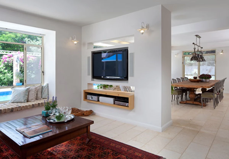 חלקת קיר מפרידה בין פינת האוכל והסלון, ושני פתחים אופקיים שנפרצו בה שומרים על קשר בין האזורים.