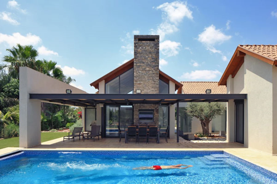 חזית אחורית, מבט מכיוון המדשאה: שלושת המבנים מתכנסים סביב פטיו, השקיפות מאפשרת קשרי עין ישירם מחוץ לפנים ולהפך.