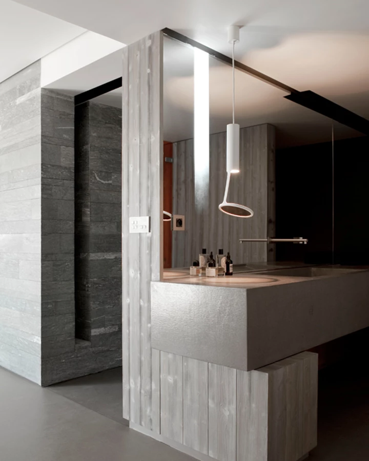 חלל הרחצה המאופיין בעיצוב מינימליסטי, נזירי ומאופק המשלב בין עץ אשוח, אבן קוורץ ובטון. הכיור עוצב כמסה מלבנית עשויה כמקשה אחת סטרוקטורת מתכת בציפוי בטון, ומעליה מראה המשלבת תאורה נסתרת.